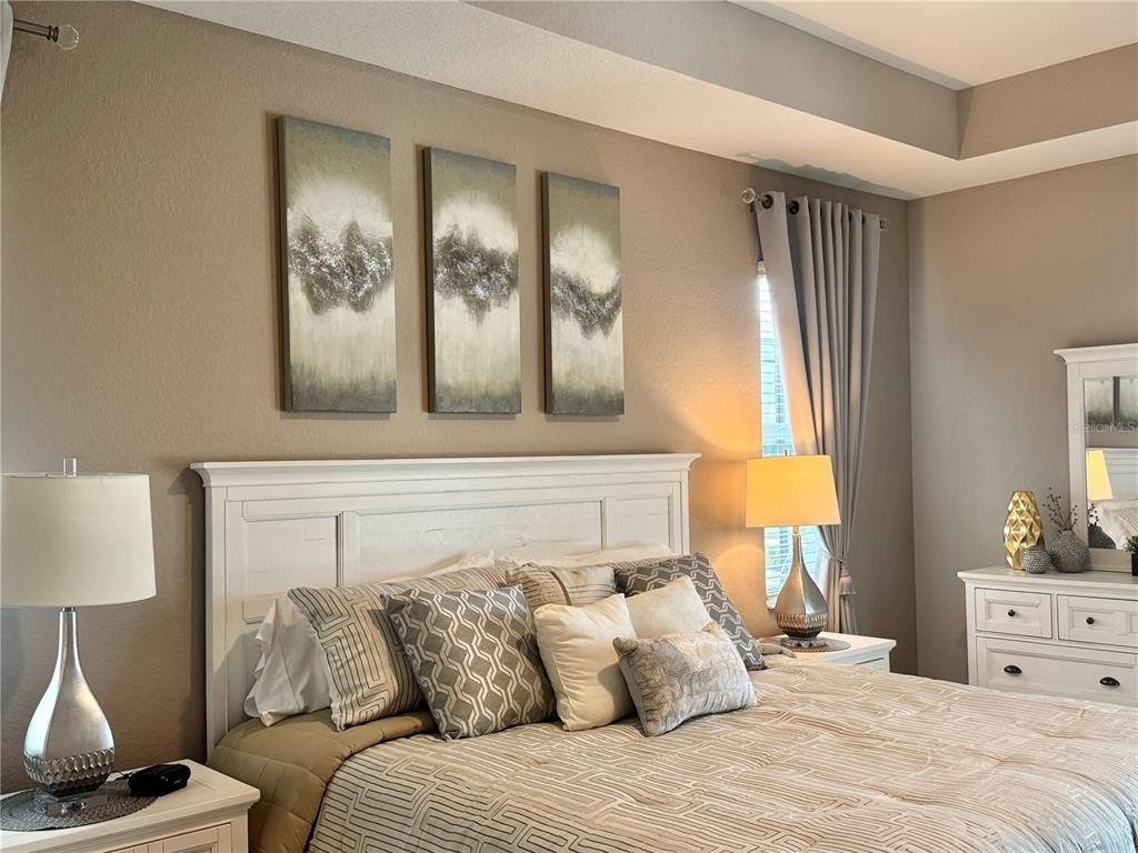 A bedroom features a white headboard, three abstract wall paintings, and matching bedside lamps — 19146 CHERRYSTONE WAY, LAKEWOOD RANCH, FL