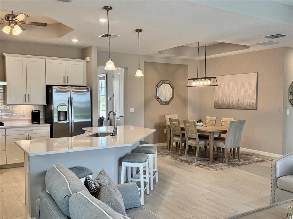 A kitchen with a breakfast bar and dining area featuring light wood-look tile flooring — 19146 CHERRYSTONE WAY, LAKEWOOD RANCH, FL
