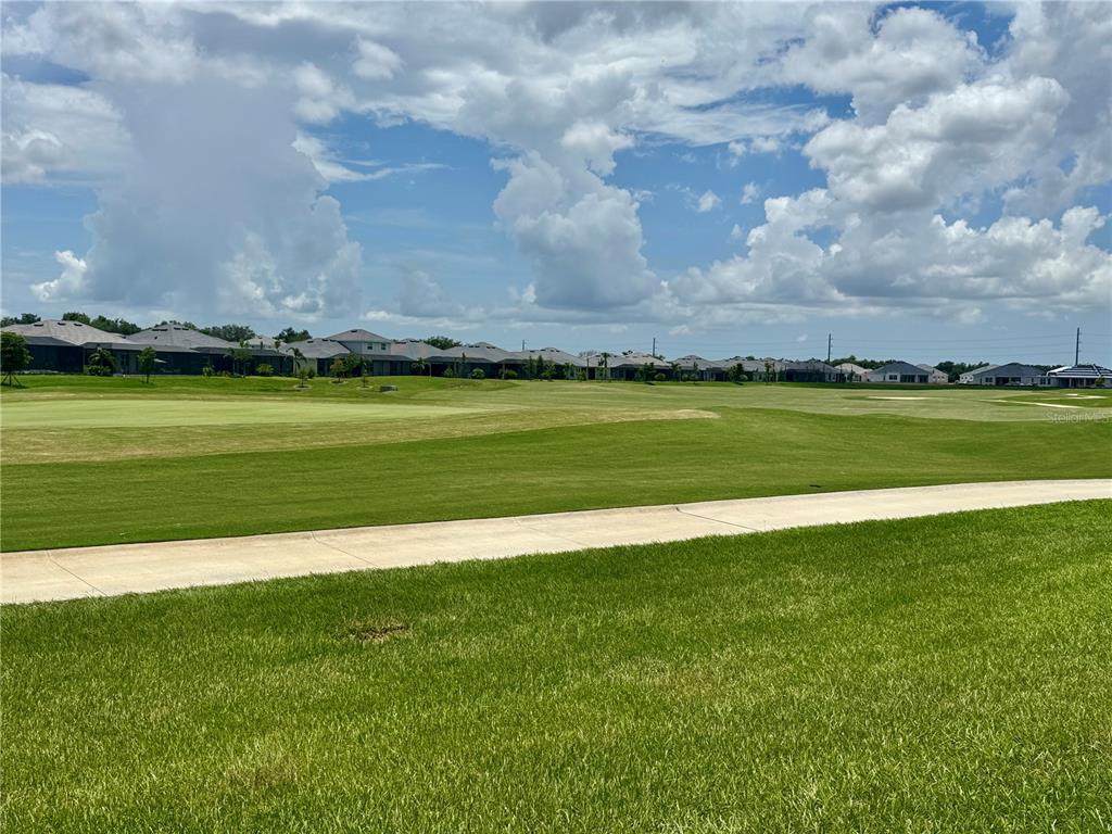 A view of a golf course fairway with houses in the background under a cloudy sky — 19146 CHERRYSTONE WAY, LAKEWOOD RANCH, FL