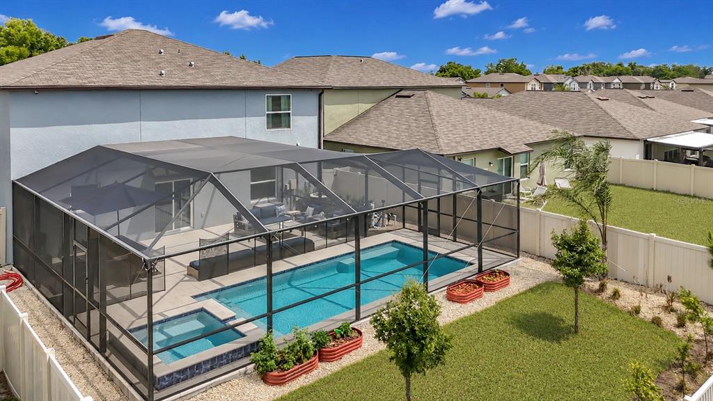 An aerial view of a backyard featuring a screened-in pool, spa, and patio area — 5519 BLUE AZURE DRIVE, WIMAUMA, FL