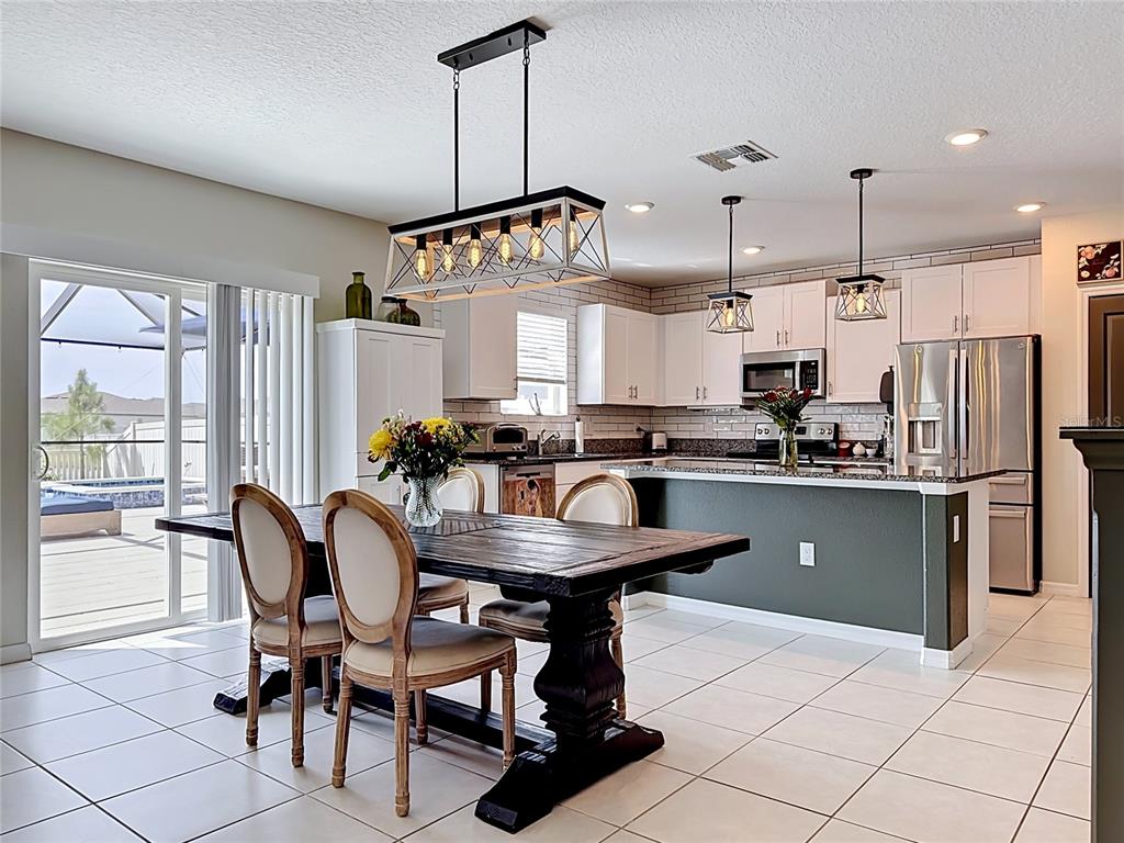 A dining area with a wooden table and chairs sits adjacent to a modern kitchen — 5519 BLUE AZURE DRIVE, WIMAUMA, FL
