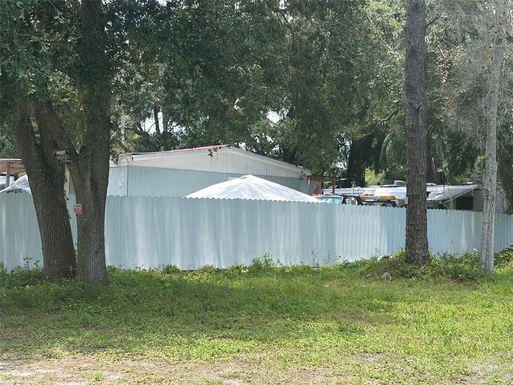 A light-colored mobile home is partially visible behind a tall white privacy fence — 18533 16TH AVENUE, ORLANDO, FL