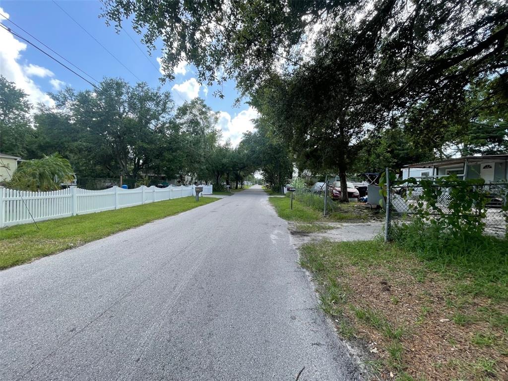 A paved residential street lined with trees, a white picket fence, and a chain-link fence — 18533 16TH AVENUE, ORLANDO, FL