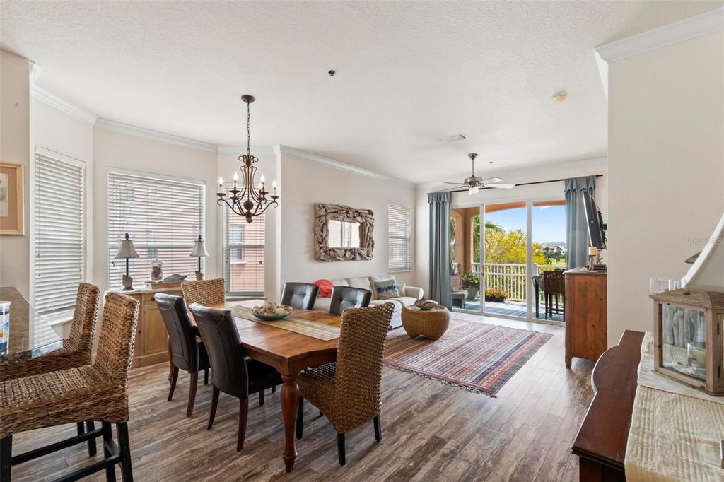 An open-concept dining and living area features wood-look flooring, a chandelier, and a balcony view — 35 OCEAN CREST WAY UNIT 1135, PALM COAST, FL