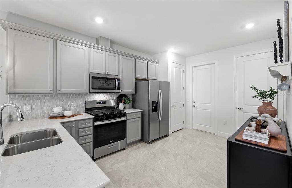 A kitchen features gray cabinets, stainless steel appliances, white countertops, and a tiled backsplash — 18809 INDIAN ROCK PLACE, LAKEWOOD RANCH, FL