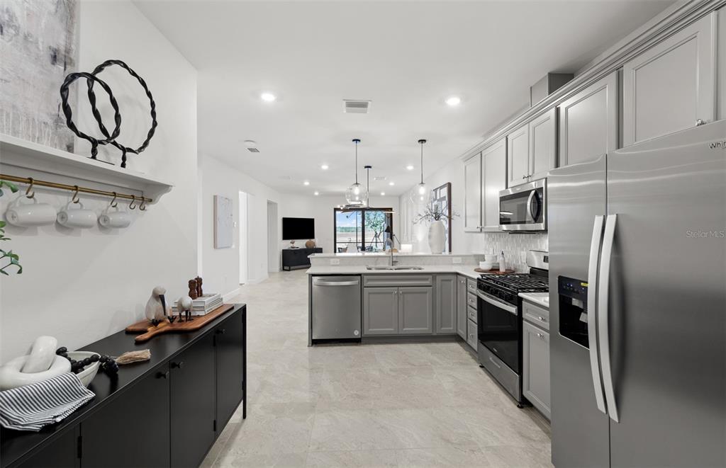 A modern kitchen features gray cabinetry, stainless steel appliances, and a black sideboard — 18809 INDIAN ROCK PLACE, LAKEWOOD RANCH, FL