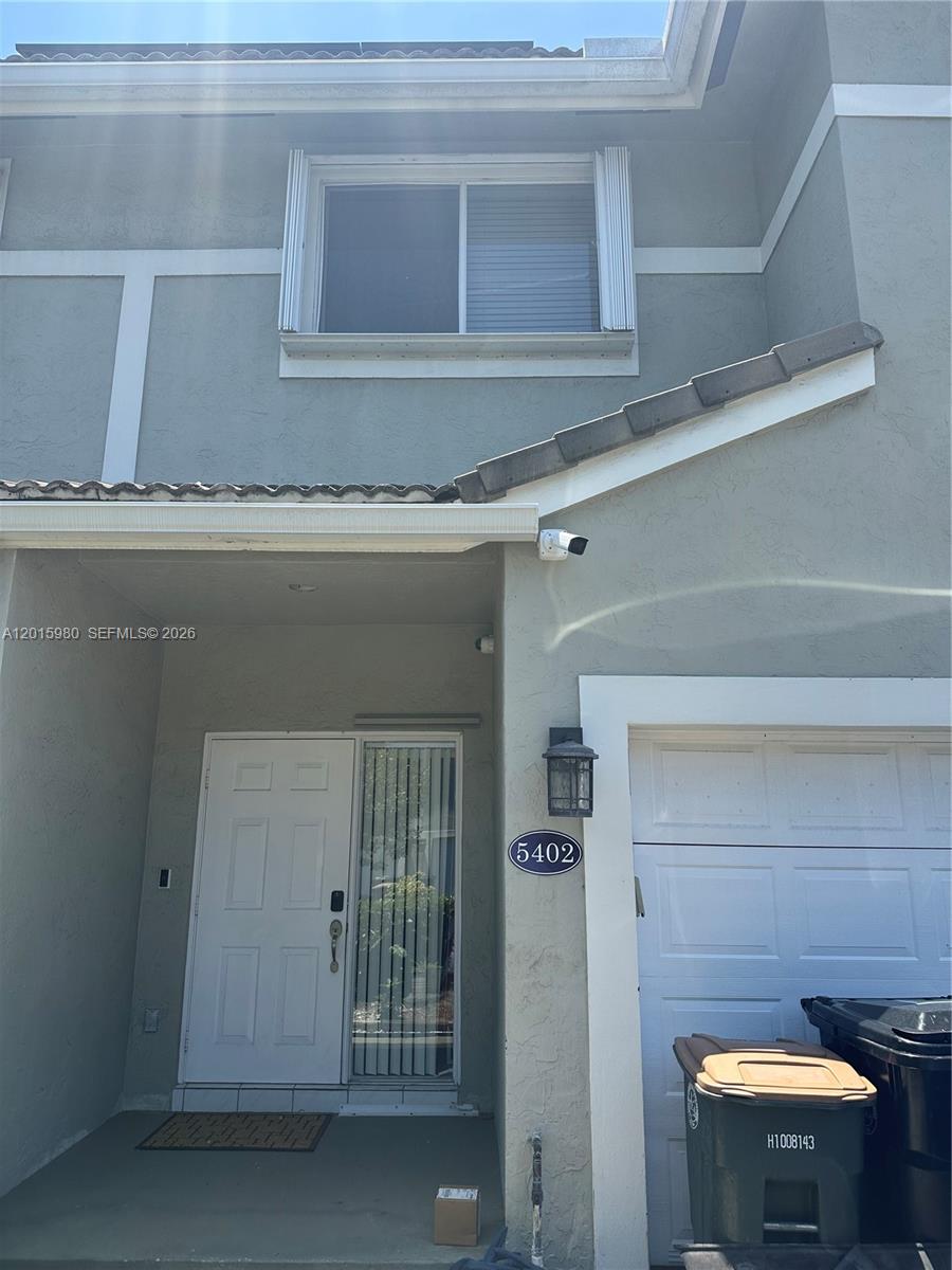 A two-story residential building exterior features a white front door, garage, and a security camera — 5402 Pointe Villa Dr # B, Lighthouse Point FL 33064, LIGHTHOUSE POINT, FL