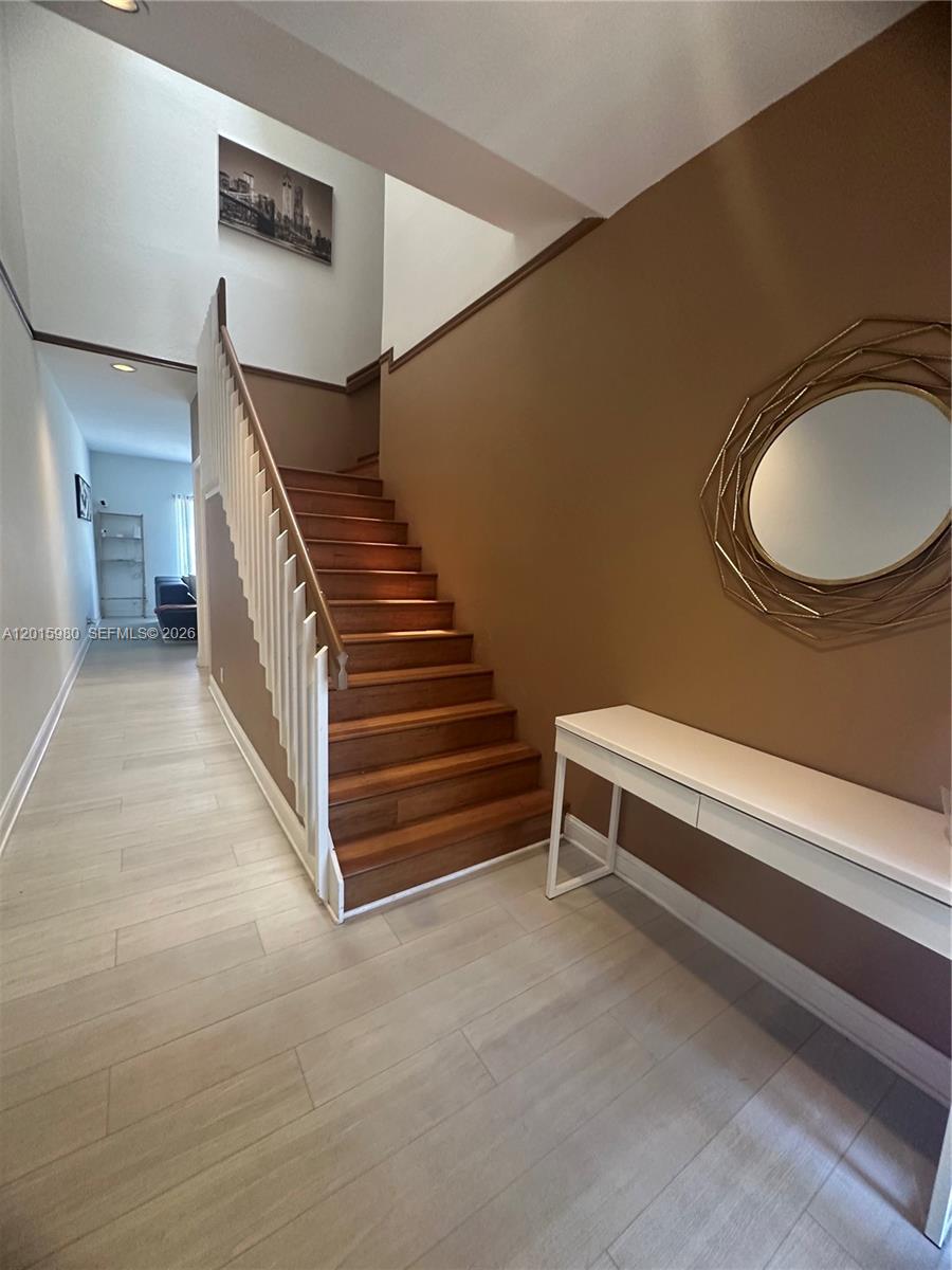 A staircase with wooden steps and a white railing sits beside a tan wall — 5402 Pointe Villa Dr # B, Lighthouse Point FL 33064, LIGHTHOUSE POINT, FL