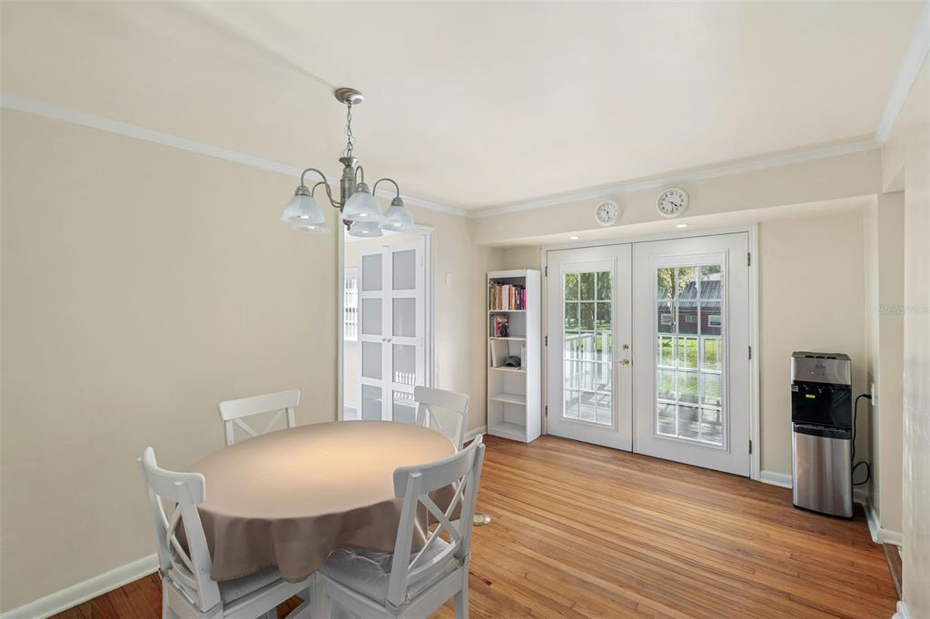 A dining area with a round table, white chairs, hardwood floors, and French doors — 15626 LARKSPUR STREET, ORLANDO, FL