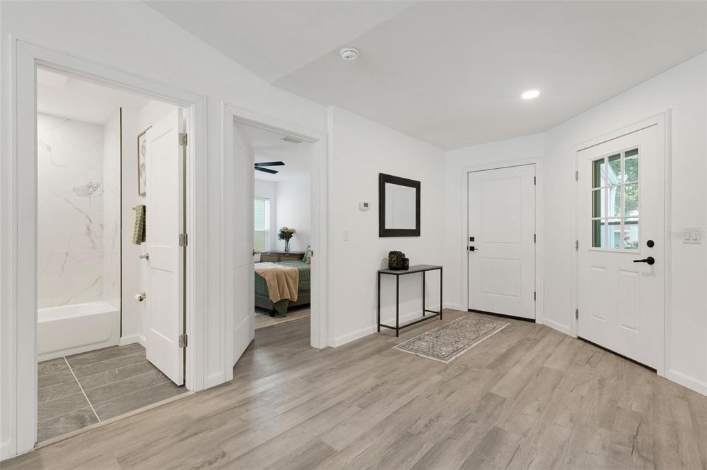 A bright entryway features light wood-look flooring, white walls, a console table, and two doors — 606 MARCUS STREET UNIT 26, VENICE, FL