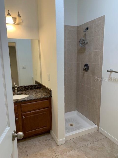 A bathroom features a wood vanity with a granite countertop and a tiled shower stall — 4247 TYLER CIRCLE N, ST PETERSBURG, FL