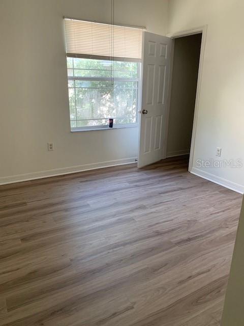 An empty bedroom features light wood-look flooring, a window with blinds, and an open doorway — 4247 TYLER CIRCLE N, ST PETERSBURG, FL