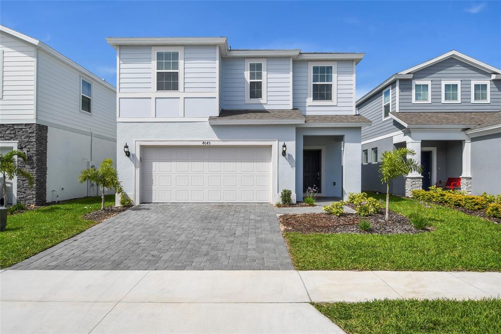 A two-story house with light blue siding, a two-car garage, and a paved driveway — 4045 LANA AVENUE, DAVENPORT, FL
