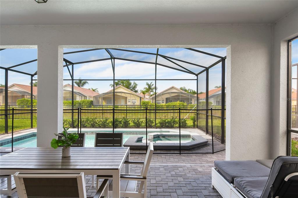 A covered patio overlooks a screened-in swimming pool and hot tub in a residential backyard — 4045 LANA AVENUE, DAVENPORT, FL