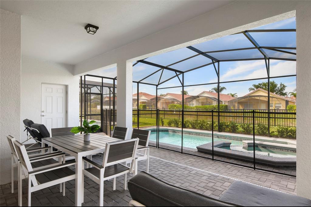 A covered patio features outdoor dining furniture, a pool, and a spa enclosed by screens — 4045 LANA AVENUE, DAVENPORT, FL