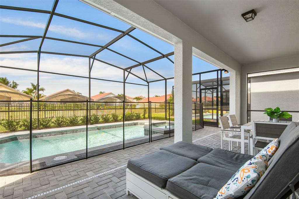A covered patio features a swimming pool, a safety fence, and outdoor lounge furniture — 4045 LANA AVENUE, DAVENPORT, FL