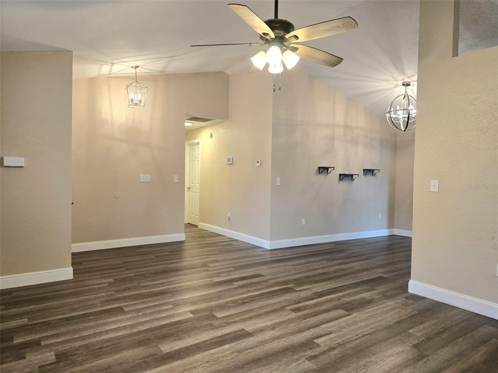 A living area features vaulted ceilings, a ceiling fan, and wood-look flooring — 326 COLONADE COURT, KISSIMMEE, FL