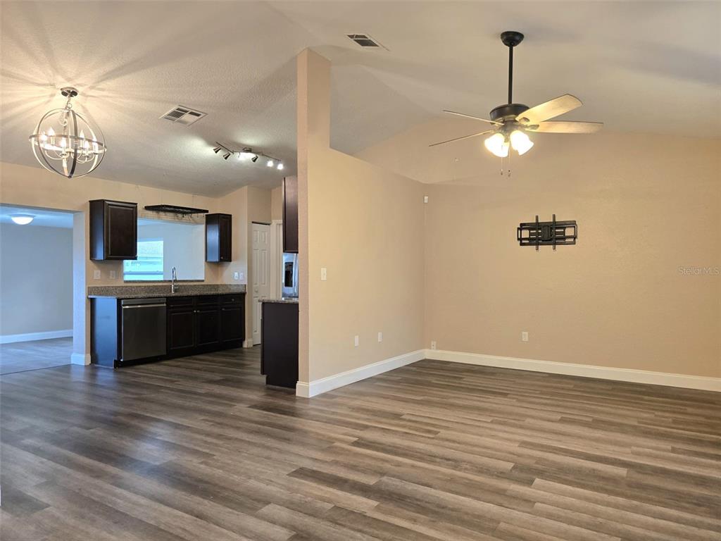 An open-concept living area features wood-look flooring, a ceiling fan, and an adjacent kitchen — 326 COLONADE COURT, KISSIMMEE, FL