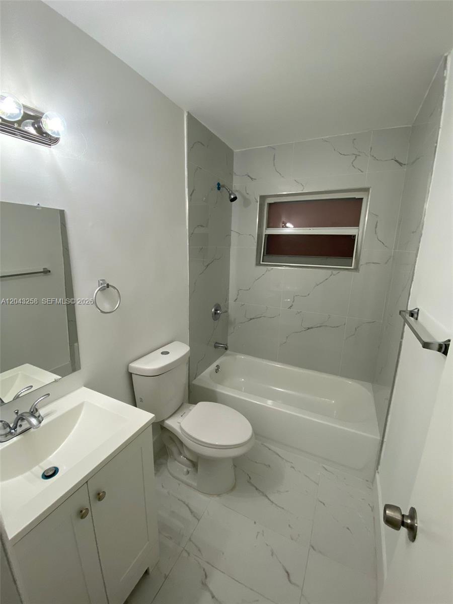 A bathroom features a white vanity, a toilet, and a tiled tub-shower combination — 1842 Madison St # 3, Hollywood FL 33020, HOLLYWOOD, FL