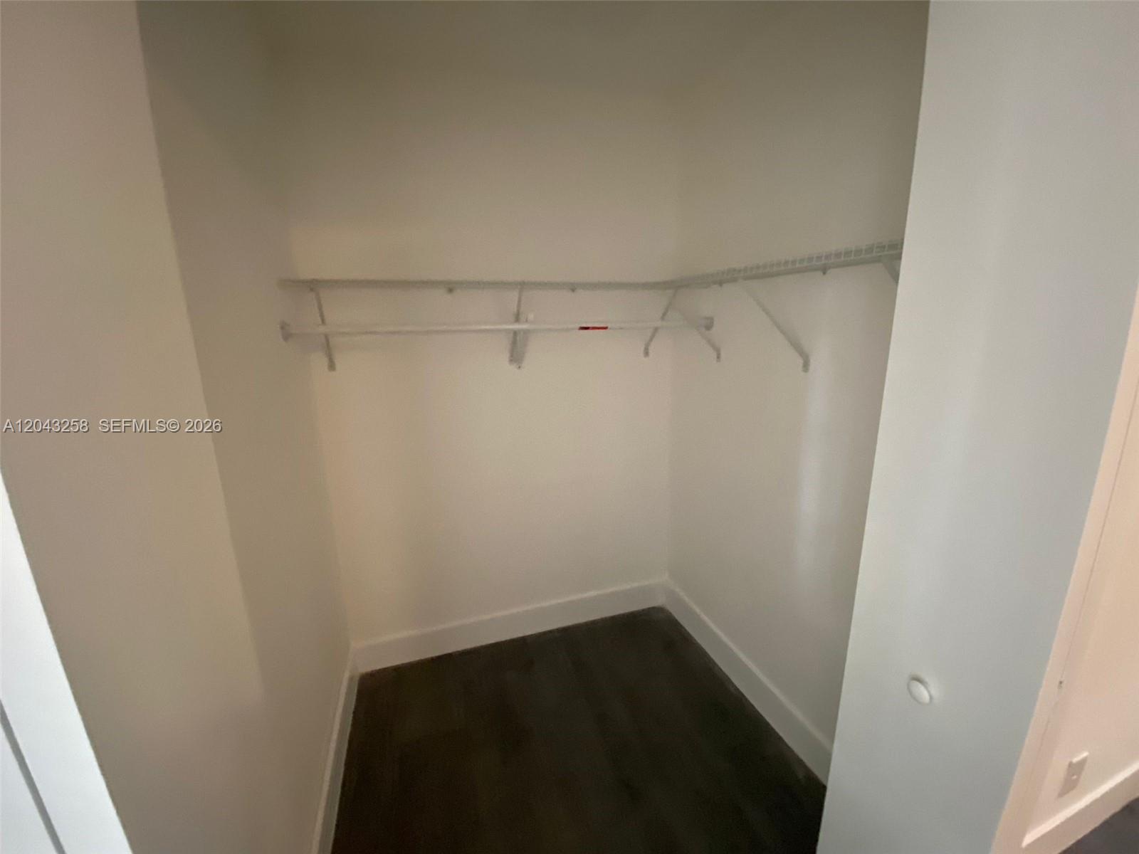 A walk-in closet features white wire shelving and dark wood-look flooring — 1842 Madison St # 3, Hollywood FL 33020, HOLLYWOOD, FL