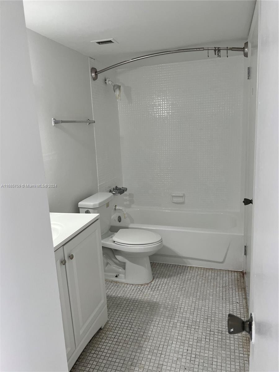A small bathroom features a white vanity, a toilet, and a tiled shower-tub combination — 498 NW 165th St Rd # 607, Miami FL 33169, MIAMI, FL