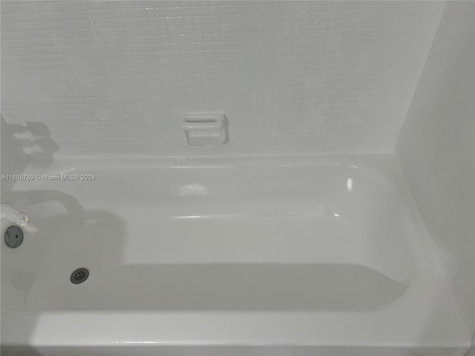 A white bathtub with a tiled wall and a built-in soap dish — 498 NW 165th St Rd # 607, Miami FL 33169, MIAMI, FL