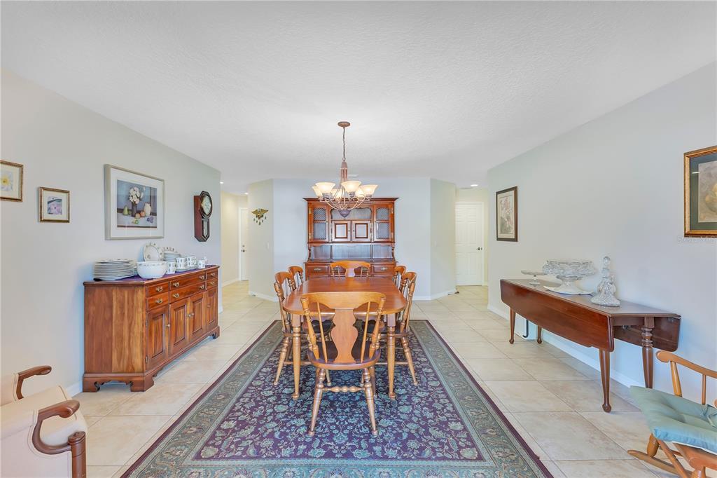A formal dining room features a wooden table, hutch, sideboard, and a patterned area rug — 1980 SUMMER COURT, KISSIMMEE, FL