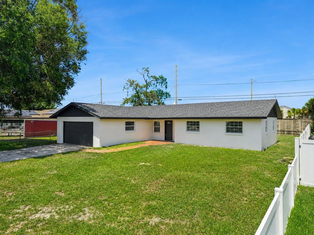 A single-story white house with a dark roof, attached garage, and a large front lawn — 937 BARBADOS AVENUE, ORLANDO, FL