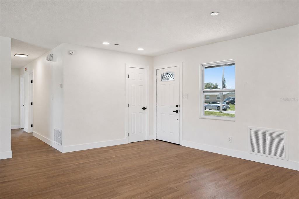 An empty room with white walls, wood-look flooring, a front door, and a window — 937 BARBADOS AVENUE, ORLANDO, FL