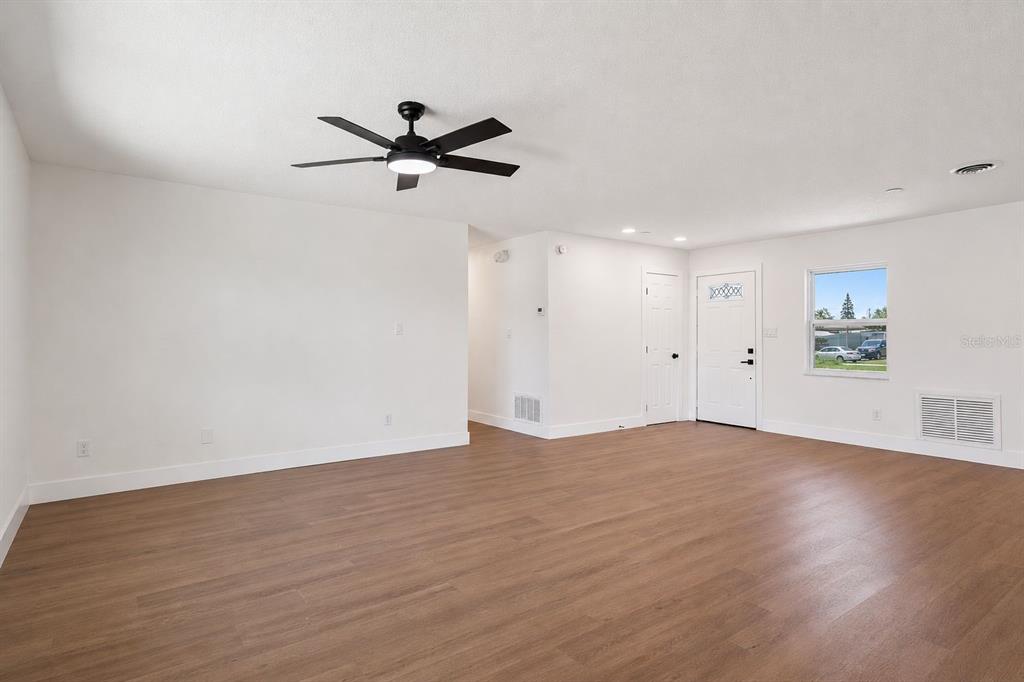 An empty room with white walls, wood-look flooring, a ceiling fan, and an exterior door — 937 BARBADOS AVENUE, ORLANDO, FL