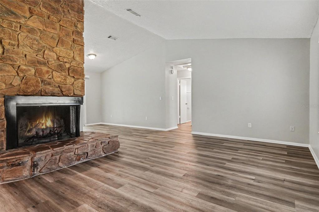 A living room features a stone fireplace, light gray walls, and wood-look laminate flooring — 629 ALTON ROAD, WINTER SPRINGS, FL