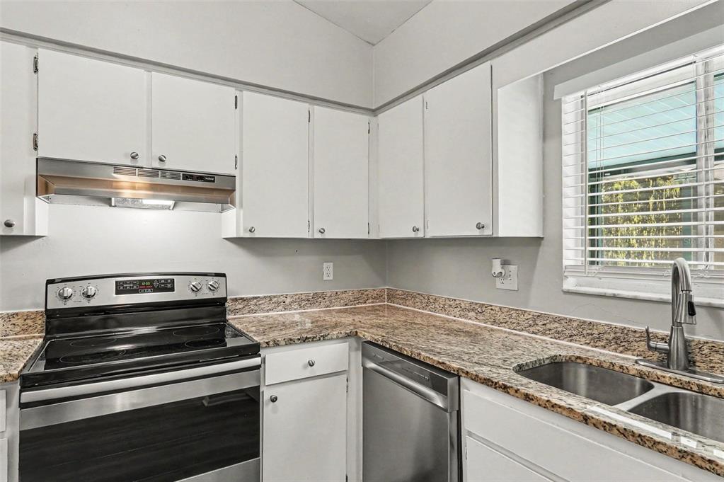 A kitchen with white cabinets, granite countertops, stainless steel appliances, and a window above the sink — 629 ALTON ROAD, WINTER SPRINGS, FL