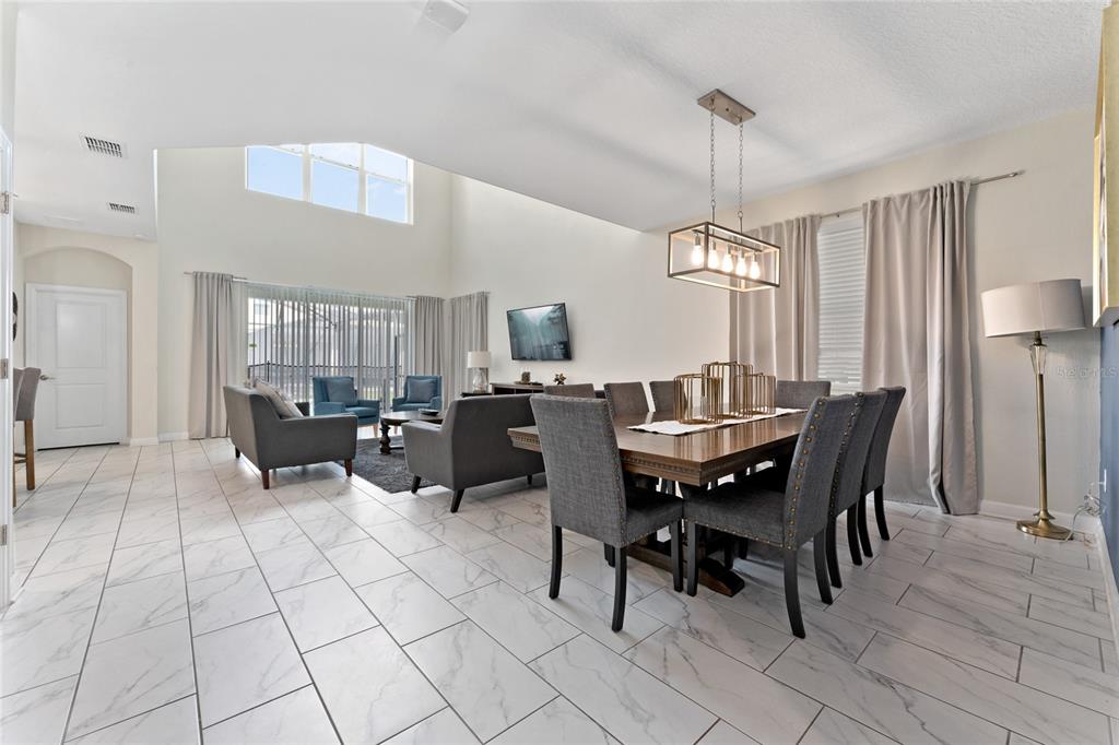 A dining area with a rectangular table and chairs sits beside a living room area — 2734 BOOKMARK DRIVE, KISSIMMEE, FL