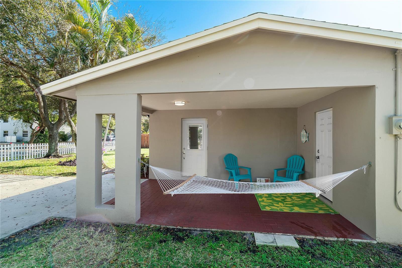 A covered patio features a white hammock, two turquoise chairs, and a red brick floor — 1634 NE 3rd Avenue, Delray Beach FL 33444, DELRAY BEACH, FL