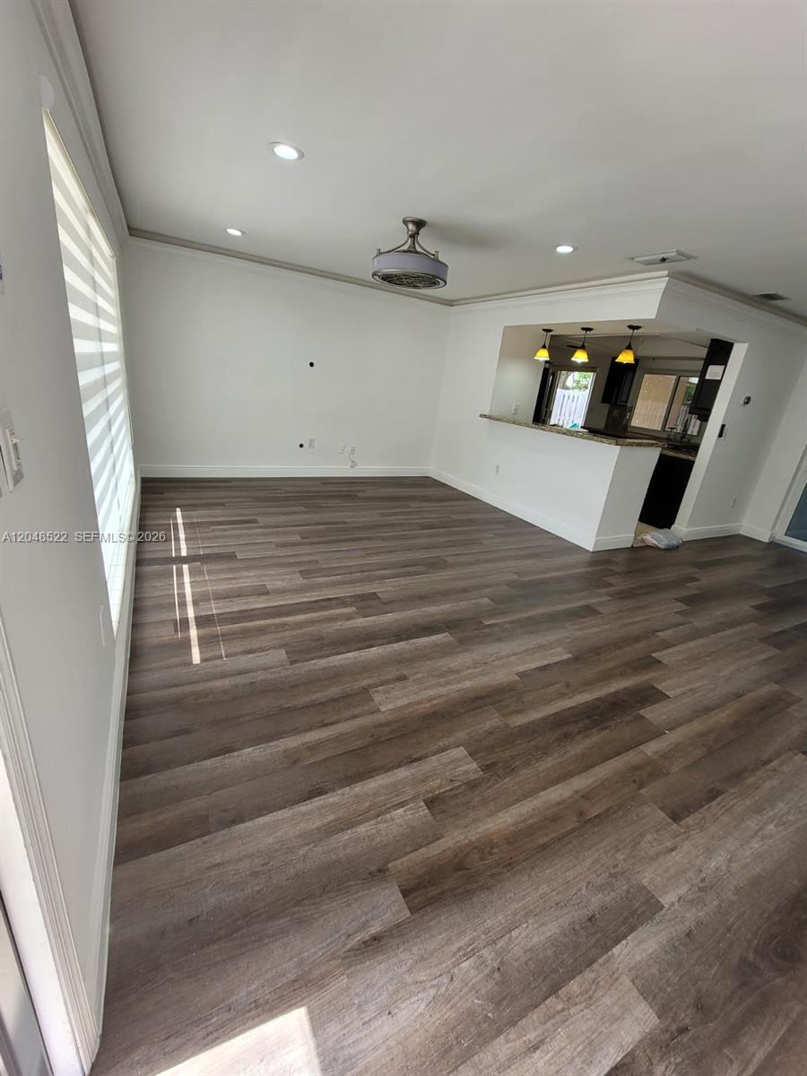 This room features wood-look flooring, white walls, recessed lighting, and a kitchen breakfast bar — 8461 NW 27th Pl, Sunrise FL 33322, SUNRISE, FL