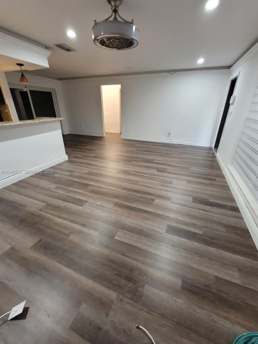 An empty room features wood-look flooring, recessed lighting, a ceiling fan, and a kitchen counter — 8461 NW 27th Pl, Sunrise FL 33322, SUNRISE, FL