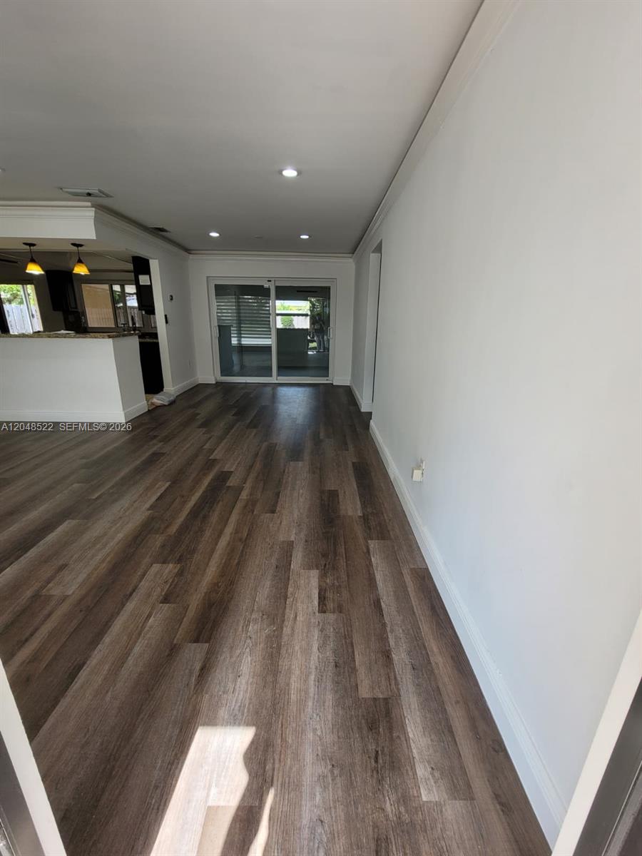 An open living area features wood-look flooring, recessed lighting, and sliding glass doors to outside — 8461 NW 27th Pl, Sunrise FL 33322, SUNRISE, FL