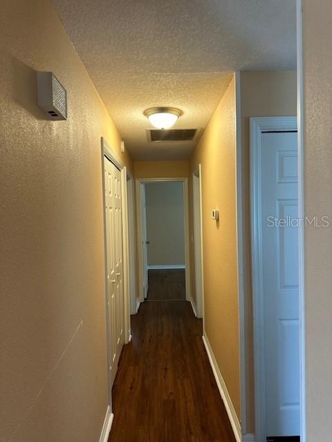 A hallway with wood-look flooring leads to a doorway at the end — 5133 OLD HIGHWAY 37, LAKELAND, FL