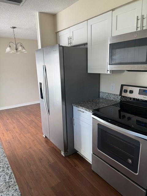 A kitchen features white cabinets, stainless steel appliances, and wood-look flooring — 5133 OLD HIGHWAY 37, LAKELAND, FL