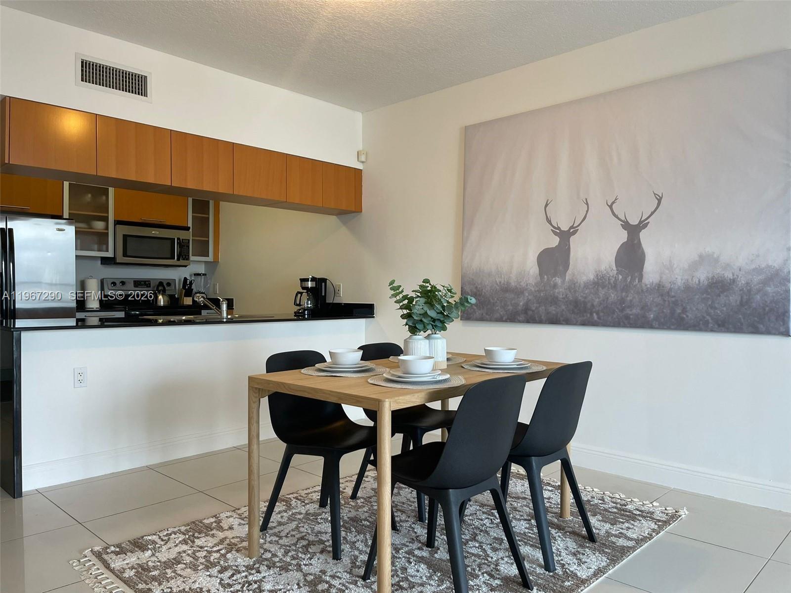 A dining area with a wooden table, four black chairs, and a large deer wall art — 1750 N Bayshore Dr # 2710, Miami FL 33132, MIAMI, FL