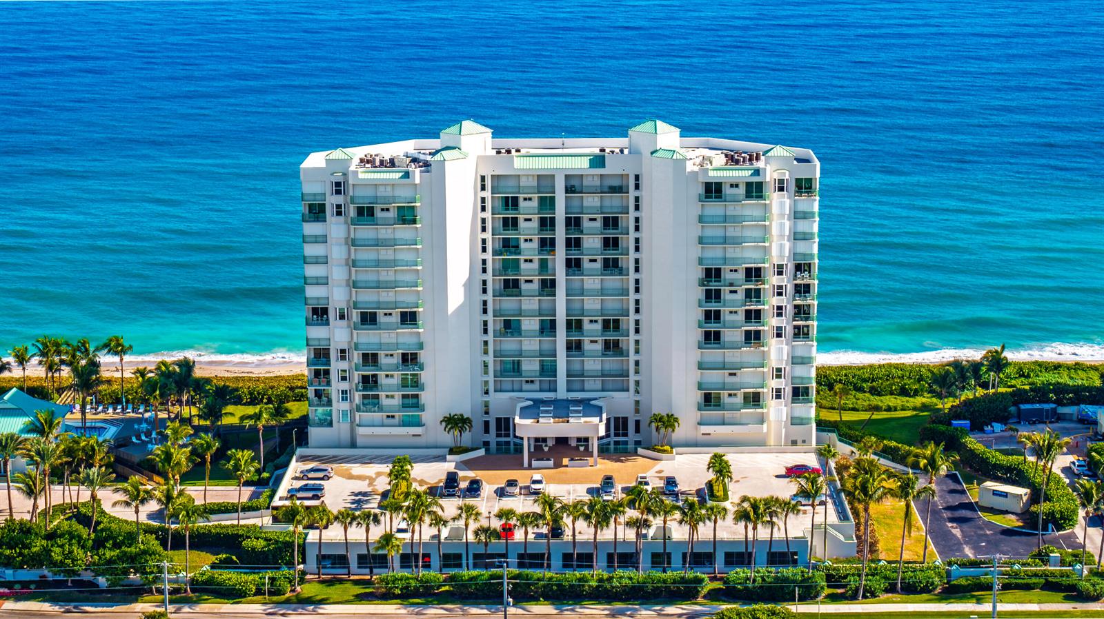 An aerial view of a multi-story beachfront condominium building with a parking lot and landscaping — 8650 S Ocean Drive # 301, Jensen Beach FL 34957, JENSEN BEACH, FL