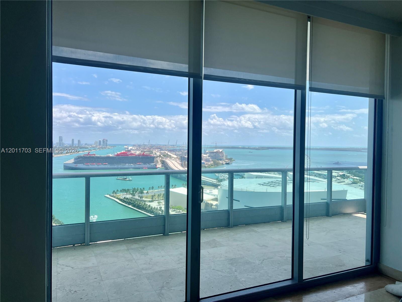 A modern kitchen island with a sink faces floor-to-ceiling windows overlooking a coastal city — 900 Biscayne Blvd # 2904, Miami FL 33132, MIAMI, FL