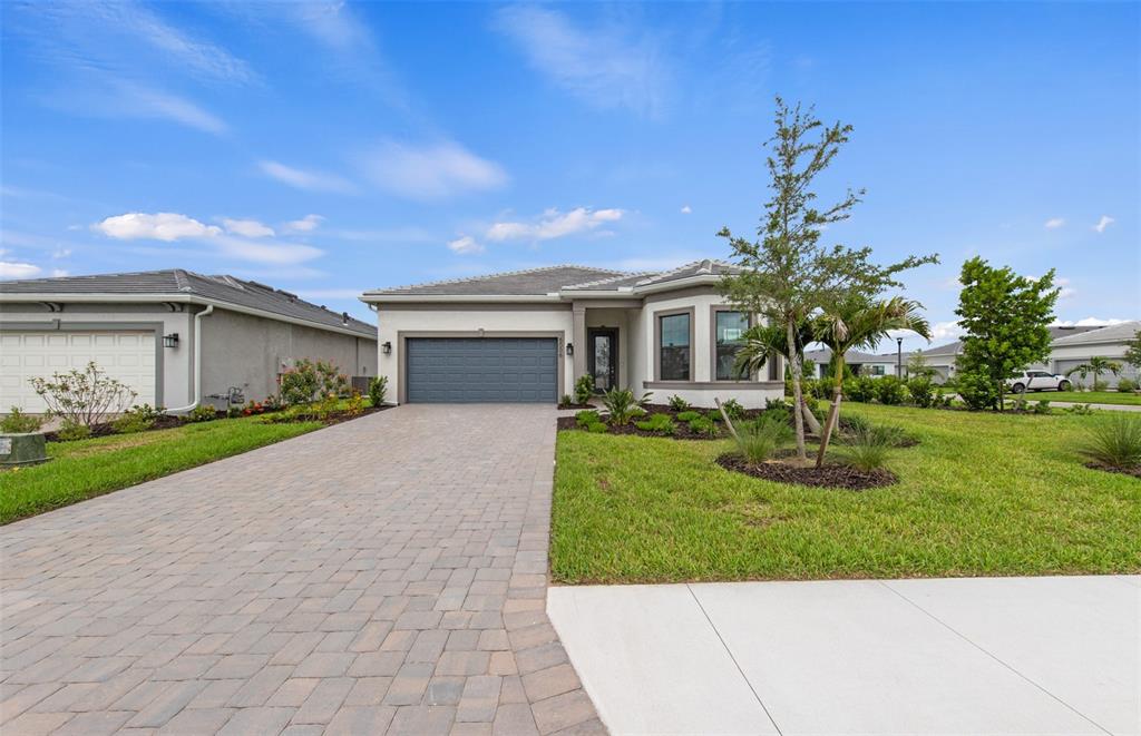 A single-story house with a paved driveway, gray garage door, and a landscaped front yard — 5006 GOLDEN SHORE COURT, LAKEWOOD RANCH, FL