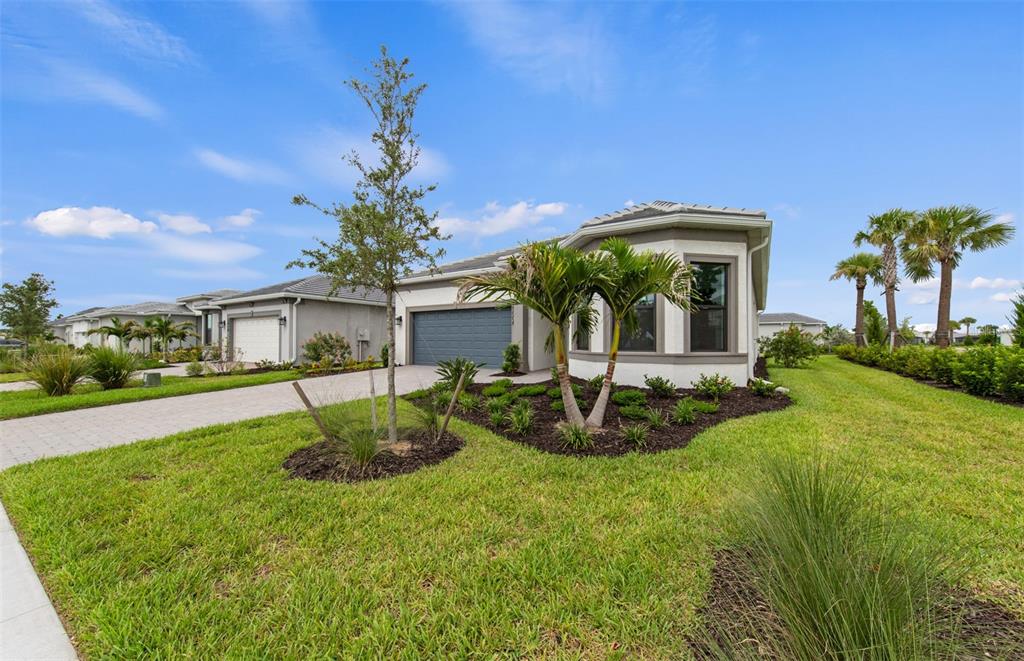 A single-story suburban house with a gray garage, palm trees, and a landscaped front yard — 5006 GOLDEN SHORE COURT, LAKEWOOD RANCH, FL