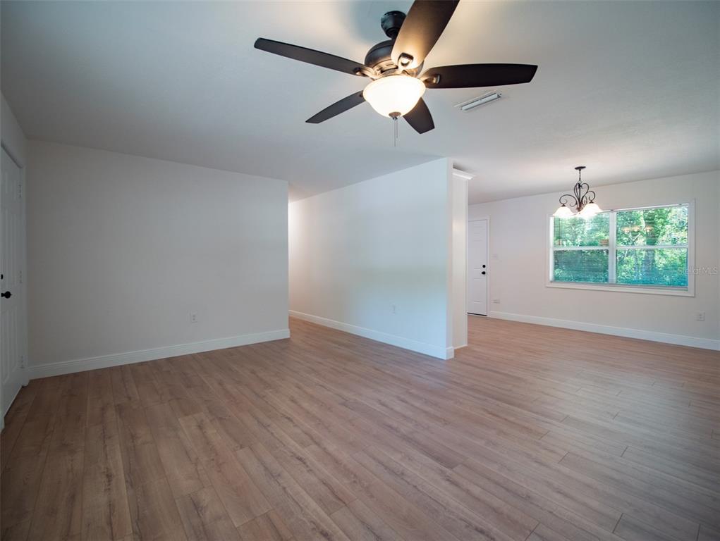 An open-concept room features light wood-look flooring, a ceiling fan, and a dining area window — 1408 6TH STREET NW, LIVE OAK, FL