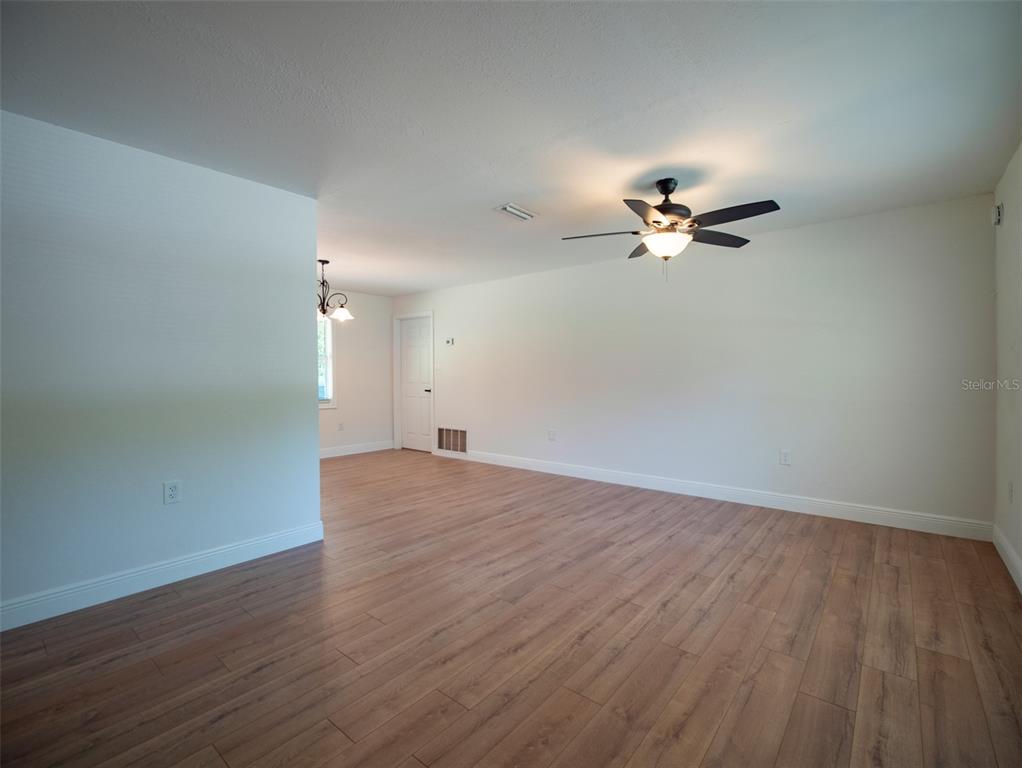 An empty room with light wood-look flooring, white walls, and a ceiling fan — 1408 6TH STREET NW, LIVE OAK, FL