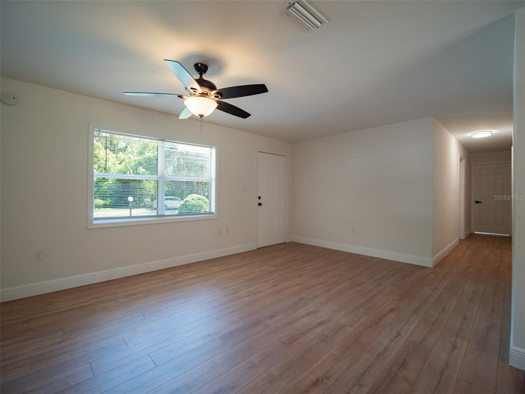 A living room features light wood-look flooring, a ceiling fan, and a window with blinds — 1408 6TH STREET NW, LIVE OAK, FL