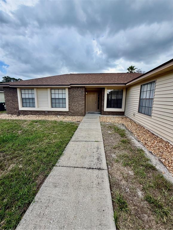 A concrete walkway leads to the front entrance of a house with brick and siding — 9132 NEW ORLEANS DRIVE, ORLANDO, FL