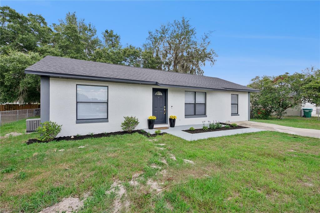 A single-story white house with a dark roof, gray door, and a concrete walkway — 65 S COURTLAND BOULEVARD, DELTONA, FL