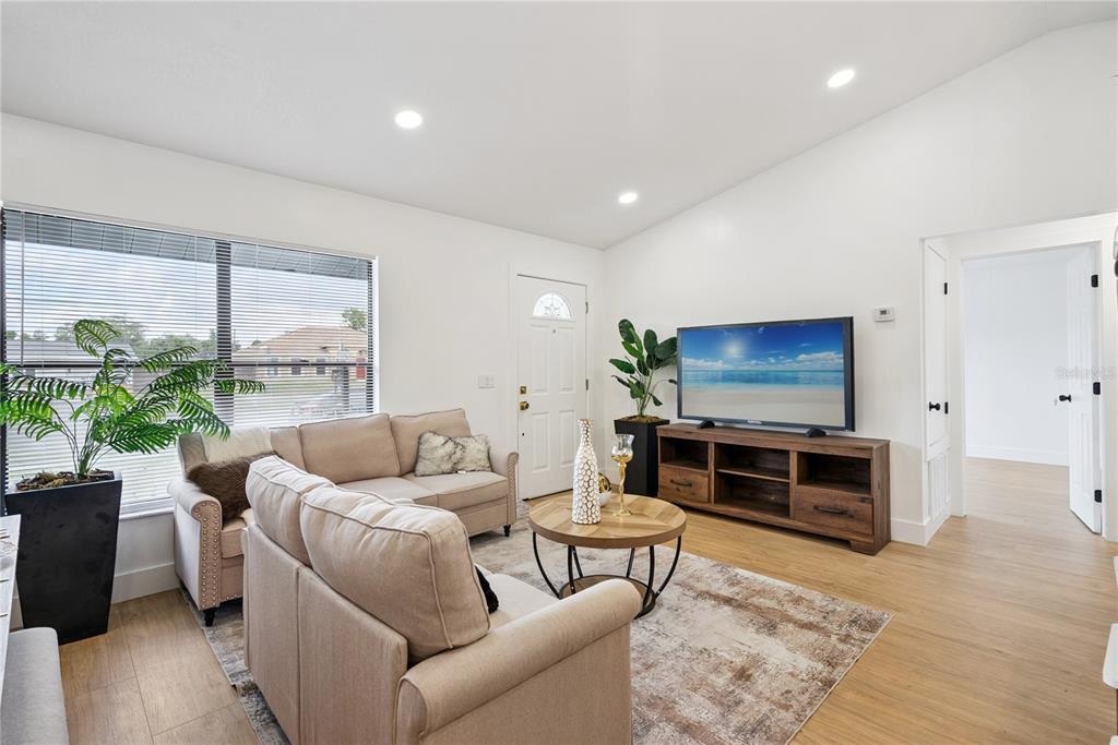 A living room features a beige sectional sofa, a wooden coffee table, and a television console — 65 S COURTLAND BOULEVARD, DELTONA, FL